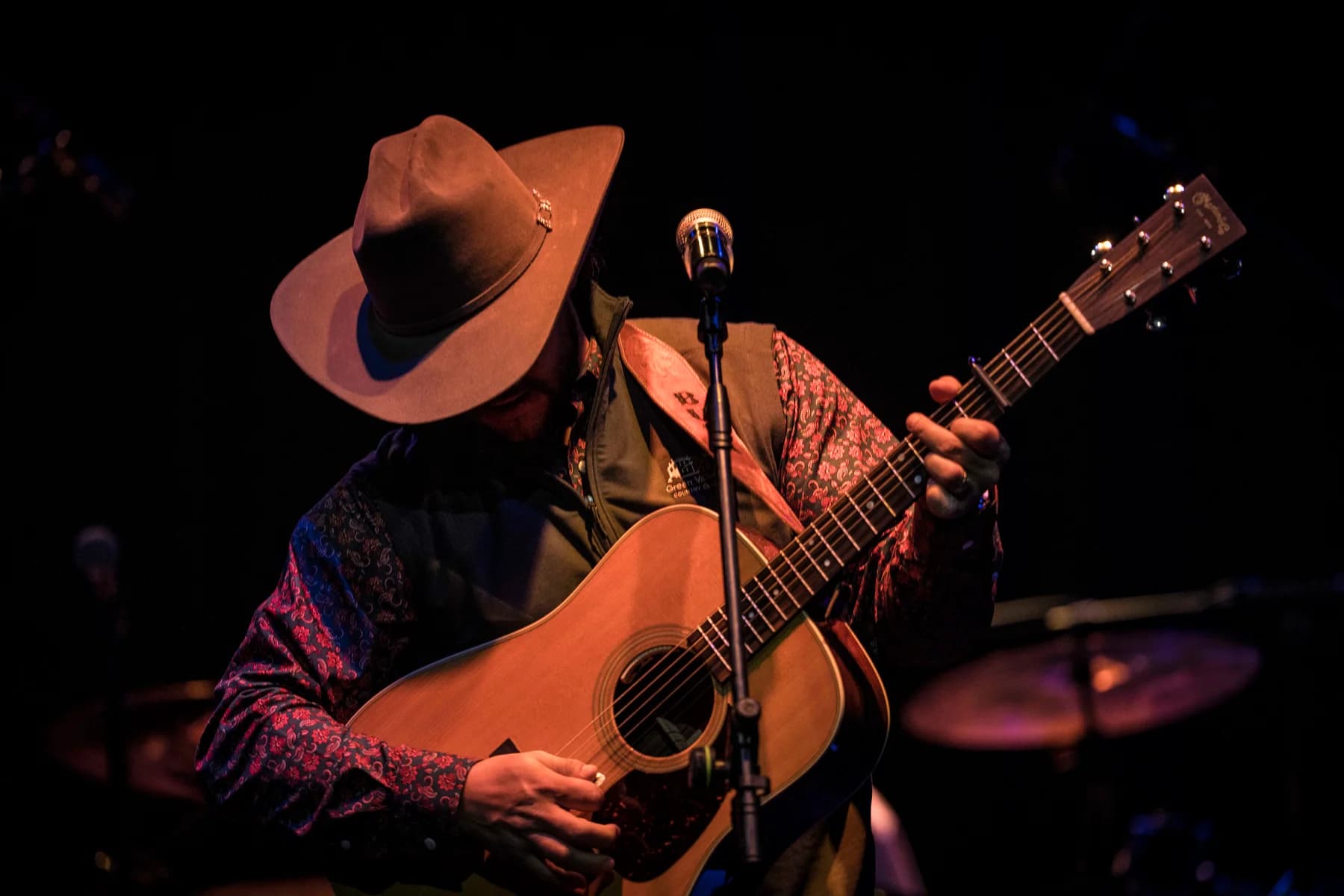 Buck Ford playing acoustic guitar under warm stage lights