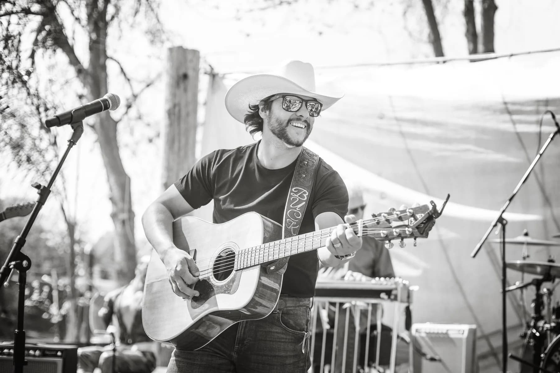 Buck Ford singing and playing guitar outdoors in black and white