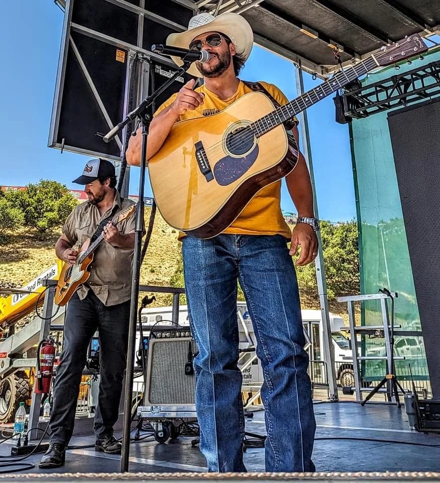 Buck Ford performing in a yellow shirt on an outdoor stage