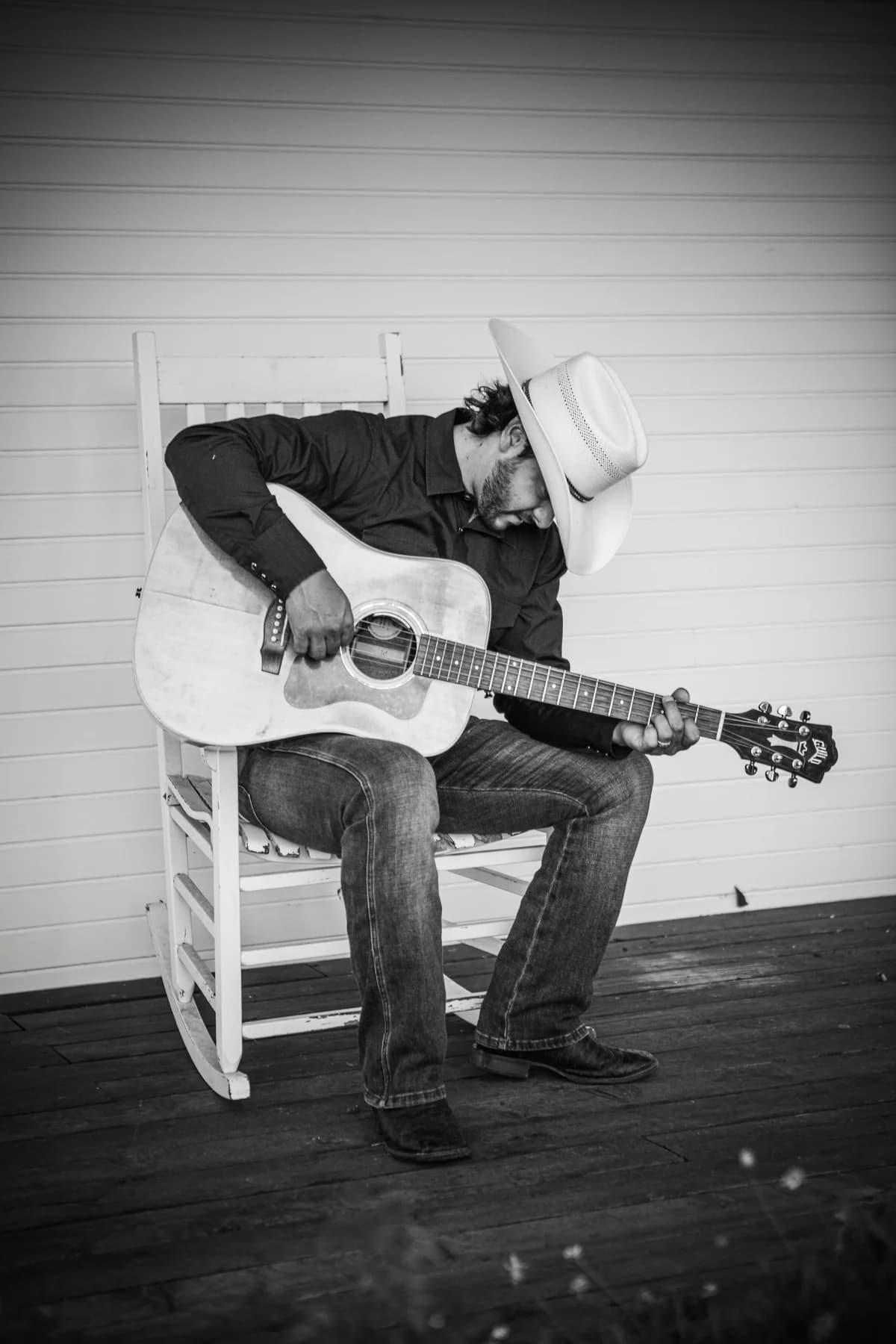 Buck Ford seated in a rocking chair with his guitar