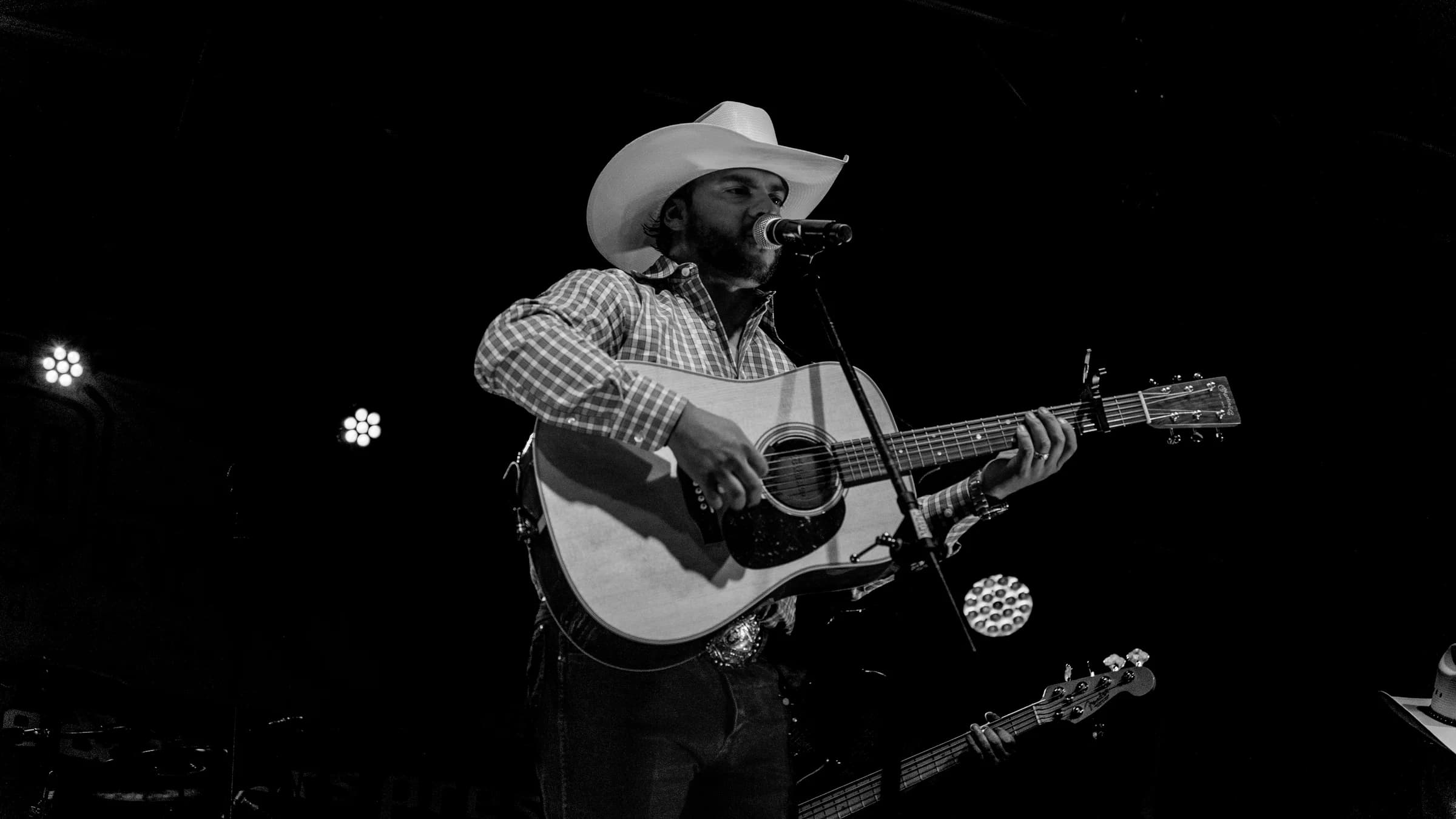 Buck Ford singing and playing acoustic guitar in a black-and-white portrait