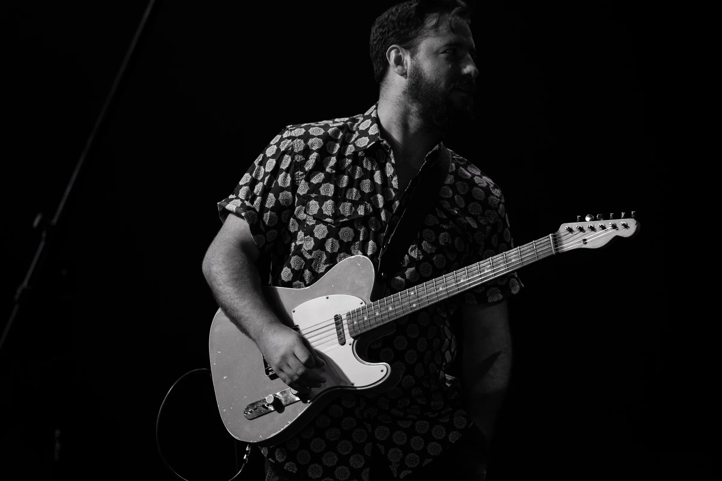 Electric guitarist in a patterned shirt, photographed in black and white