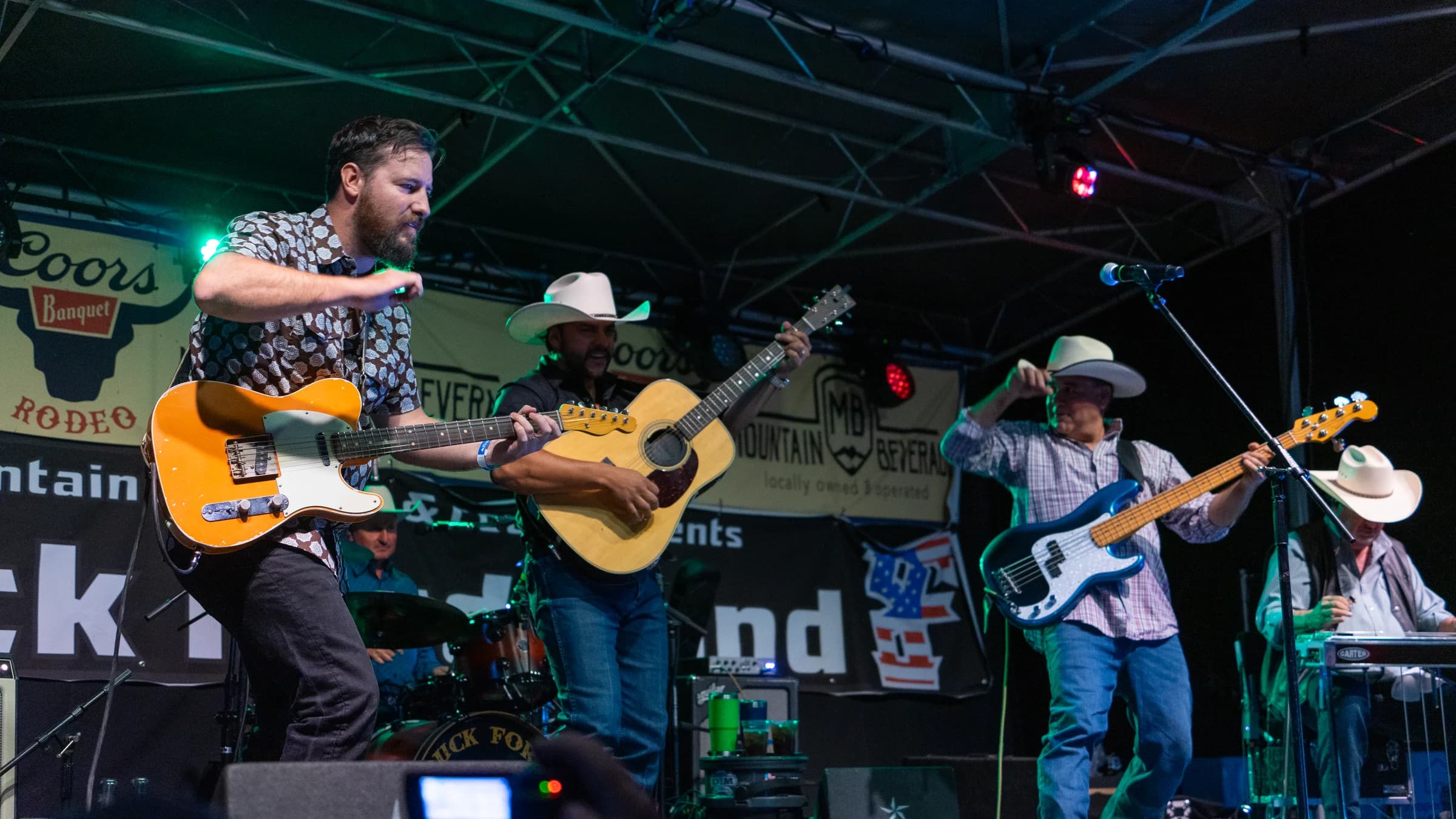 Buck Ford and the band playing beneath an outdoor stage roof
