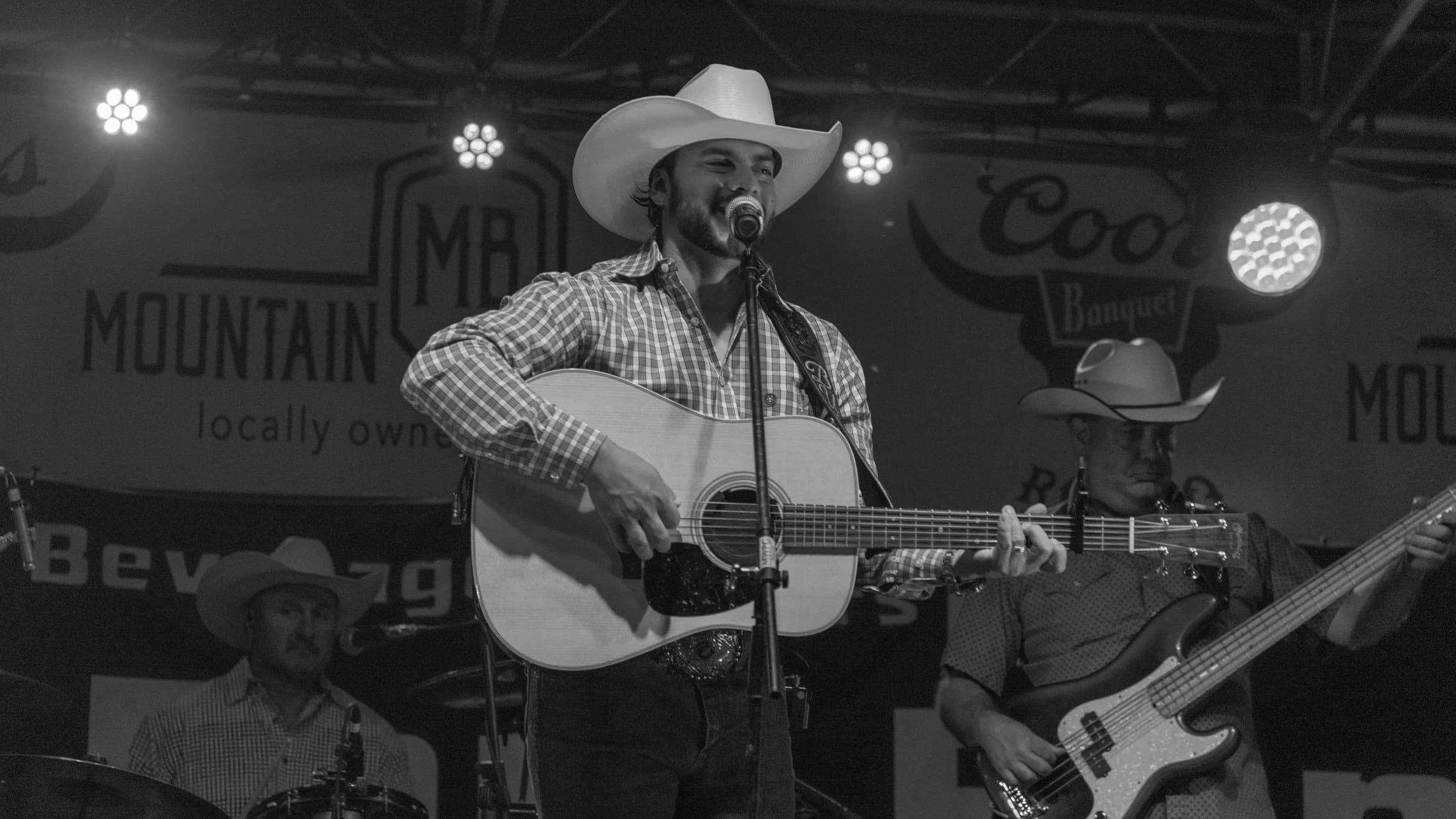 Buck Ford on stage with his acoustic guitar in black and white