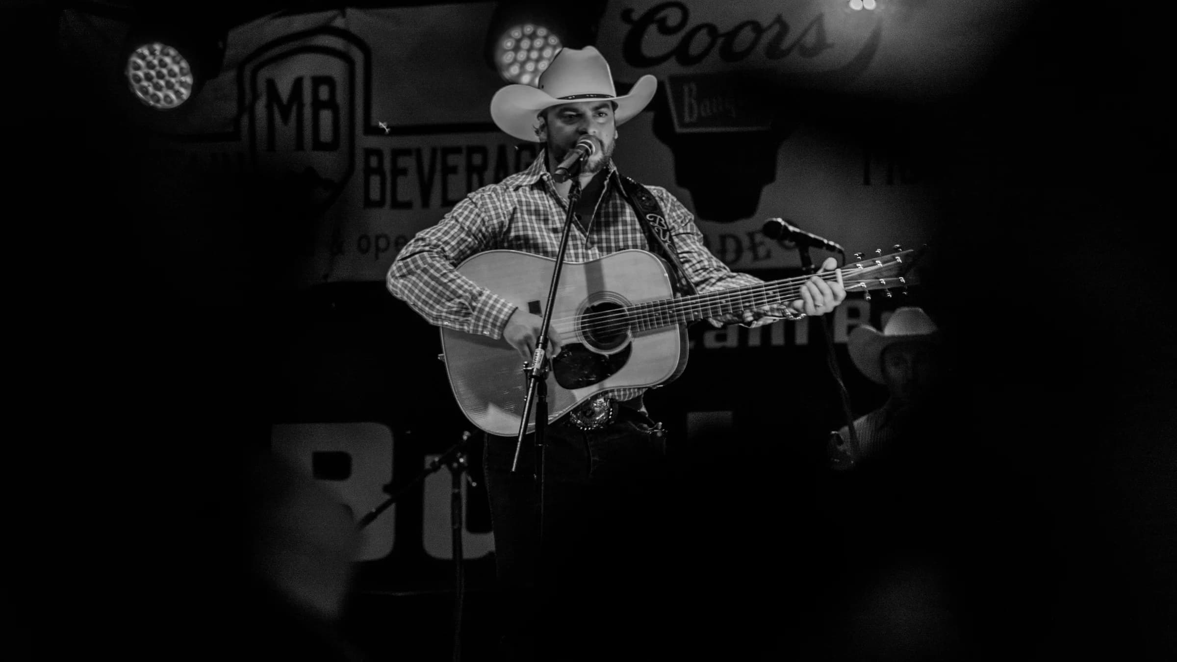 Buck Ford singing with his acoustic guitar in black and white